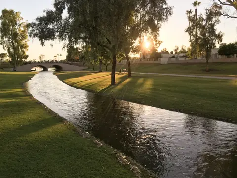 A water channel running through a grassy park in Scottsdale in late sun