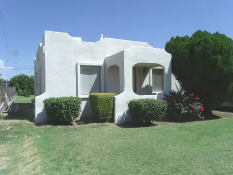 A white stucco house with green shrubs and a lawn in Peoria