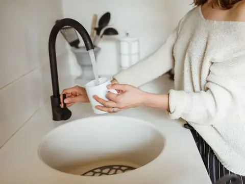 Filling a white cup with water from a black kitchen faucet
