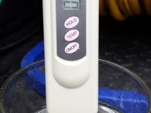 A dissolved solids meter dipped in a glass of water