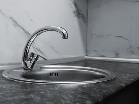 A chrome kitchen faucet over a round steel sink