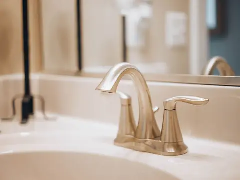 A brass faucet over a white bathroom basin