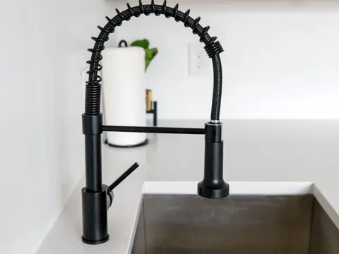 A black kitchen faucet over a white countertop
