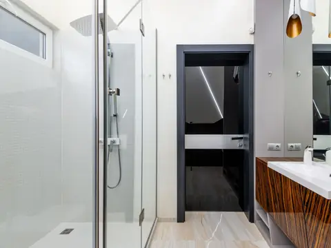 A glass-walled shower beside a vanity in a bright bathroom