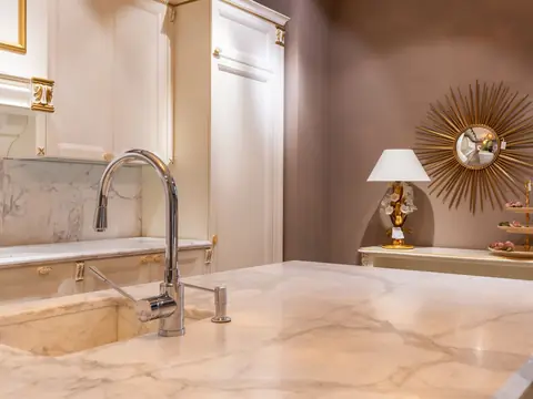 A kitchen faucet over a sink in a marble countertop