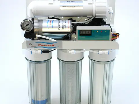 A small reverse osmosis unit with three clear filter canisters and a membrane housing on top