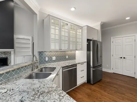 A bright kitchen with granite countertops and a sink under the window