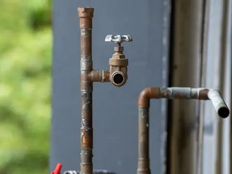 Copper water pipes with a valve and spigot on an outside wall