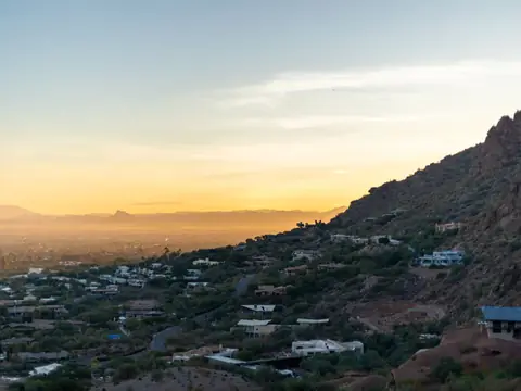 Houses across the Valley floor below desert hills at sunset near Phoenix