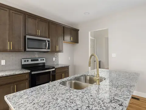 A kitchen with a marble countertop island and stainless appliances