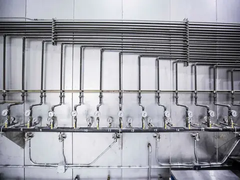 Steel water pipes with valves and pressure gauges along a wall
