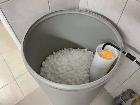 Salt pellets inside a softener brine tank, the brine well at the side