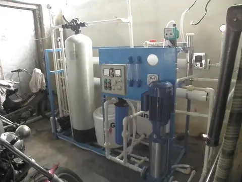 A tall treatment tank with its control valve on top, piped into a water treatment system